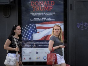 Women walk by a poster advertising U.S. President Donald Trump's speech, that reads "Donald Trump. First Public Appearance in Europe", in Warsaw, Poland