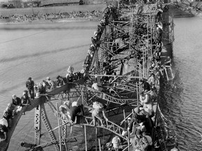 FILE - In this Dec. 4, 1950 file photo, residents from Pyongyang, North Korea, and refugees from other areas crawl perilously over shattered girders of the city's bridge as they flee south across the Taedong River to escape the advance of Chinese Communist troops. Sports ties between the rival Koreas often mirror their rocky political ties. (AP Photo/Max Desfor, File)