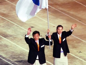 FILE - In this Sept. 15, 2000 file photo, Pak Jung Chul, left, a North Korea's Judo coach, and Chung Eun-sun, a South Korean basketball player, carry a flag representing a united Korea into Olympic Stadium during the Opening Ceremony of the Olympics in Sydney, Australia. Seven months ahead of the Pyeongchang Olympics, many in South Korea, including new liberal President Moon Jae-in, hope to use the Games as a venue to promote peace with rival North Korea. To do so, the North's participation is essential, but an ongoing nuclear tension and a lack of winter sports athletes in North Korea could ruin the attempts at reconciliation. (AP Photo/Rusty Kennedy, File)