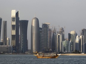 FILE - In this Thursday Jan. 6, 2011 file photo, a traditional dhow floats in the Corniche Bay of Doha, Qatar, with tall buildings of the financial district in the background. Qatar has hired a Washington influence firm founded by President Donald Trump's former campaign manager and another specialized in digging up dirt on U.S. politicians. (AP Photo/Saurabh Das, File)