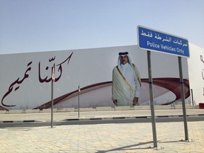 FILE- In this Monday, July 3, 2017 file photo, an image of Qatar's emir, Sheikh Tamim bin Hamad Al Thani, graces a billboard featuring the slogan "We are all Tamim" in Doha, Qatar. Qatar's answer to a list of demands from four countries lined up against it may be shrouded in secrecy, but the message it delivered this week was clear enough: it is not about to roll over. (AP Photo/Maggie Hyde, File)