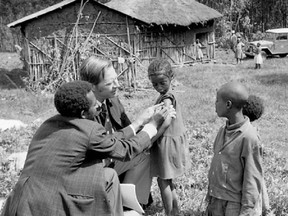 D.A. Henderson, chief of WHO's smallpox eradication unit, in the field in Ethiopia examining vaccination scars on children before the disease was eradicated.