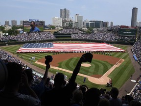 Workers hold an American flag during the singing of the national anthem before a baseball game between the Tampa Bay Rays and the Chicago Cubs on Tuesday, July 4, 2017, in Chicago. (AP Photo/Matt Marton)