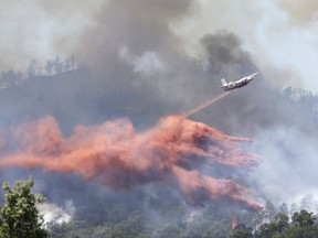 A firefighting plane drops fire retardant over a forest in the outskirts of La Londe-les-Maures on the French Riviera, Wednesday, July 26, 2017. Authorities ordered the evacuation of 10,000 people as fires hopscotched around the Riviera for a third day Wednesday, tearing through the forest of La Londe-les-Maures. (AP Photo/Claude Paris)