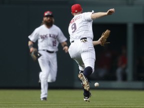 Colorado Rockies second baseman DJ LeMahieu, front, reaches out and misses a pop single off the bat of Cincinnati Reds' Jose Peraza as Rockies center fielder Charlie Blackmon comes in to cover in the first inning of a baseball game Monday, July 3, 2017, in Denver. (AP Photo/David Zalubowski)