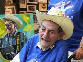 In this July 2, 2017, photo Cajun musician D.L. Menard attends an event at the Acadian Museum in his home town of Erath, La., where a portrait, seen behind him, was presented as part of a tribute to the entertainer. Menard, whose song "The Back Door" is among the most popular in Cajun music, is dead at the age of 85. Louisiana Funeral Services and Crematory in Broussard said on its website that Menard died Thursday, July 27 at his home in Scott, Louisiana. (Janet McConnaughey via AP)