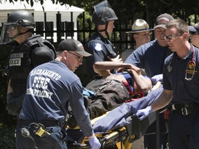 FILE - In this June 26, 2016, file photo, paramedics rush a stabbing victim to an ambulance after violence erupted during a white nationalist group's rally outside the state Capitol in Sacramento, Calif. The Sacramento County District Attorney's Office said Tuesday, July 18, 2017, that two people are being charged for alleged assault with a deadly weapon and participating in a riot. Other arrests are expected from the eight-month long investigation conducted by the California Highway Patrol. (AP Photo/Steven Styles, File)