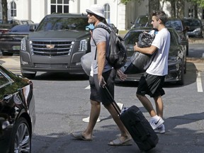 Carolina Panthers' Greg Olsen, left foreground, carries personal items from his car as he walks to the dorms as the NFL team's players arrive for the beginning of training camp at Wofford College in Spartanburg, S.C., Tuesday, July 25, 2017. The team has several issues looming including how much Cam Newton will throw and whether Thomas Davis and Greg Olsen will receive contract extensions. (AP Photo/Chuck Burton)