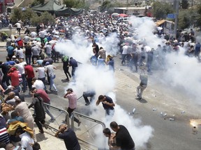 Palestinians run away from tear gas thrown by Israeli police officers outside Jerusalem's Old City, Friday, July 21, 2017.