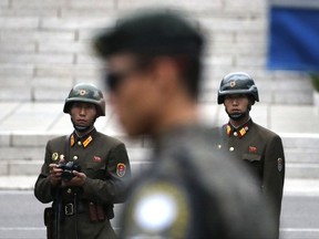 FILE - In this April 17, 2017, file photo, two North Korean soldiers look at the south side as a South Korean soldier, center, stands guard while U.S. Vice President Mike Pence visited the border village of Panmunjom which has separated the two Koreas since the Korean War, South Korea. South Korea has offered on Monday, July 17, 2017 to talk with North Korea to ease animosities along their tense border and resume reunions of families separated by their war in the 1950s. (AP Photo/Lee Jin-man, File)