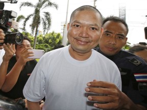 Fugitive ex-monk Wirapol Sukphol is escorted by the Department of Special Investigation officials to the prosecutor's office in Bangkok, Thailand, Thursday, July 20, 2017. Wirapol, wanted on charges including child molestation and fraud, is back in Thailand after being extradited from the United States, where he fled in 2013. (AP Photo/Sakchai Lalit)