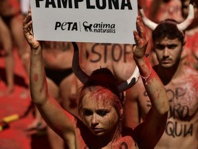 A demonstrator holds up a placard against bullfighting, her body covered with red dust during a protest a day before of the San Fermin festival, in Pamplona, northern Spain, Wednesday, July 5, 2017. The festival will begin on July 6 with the ''txupinazo'' opening ceremony, with people participating in bull runs, music and dance, through the old city. (AP Photo/Alvaro Barrientos)