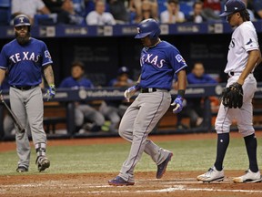 Texas Rangers' Mike Napoli, left, looks on as Adrian Beltre, center, scores from third base on a wild pitch by Tampa Bay Rays starter Chris Archer, right, during the sixth inning of a baseball game Saturday, July 22, 2017, in St. Petersburg, Fla. (AP Photo/Steve Nesius)