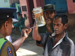 A Sri Lankan public health official,left, points out Mosquito lava in a bottle during a Dengue fever irradiation work in Colombo, Sri Lanka, Tuesday, July 4, 2017. Sri Lanka is suffering its worst dengue outbreak with more than 200 people killed and 76,000 infected this year. Alarmed by the scale of disease, the island nation has deployed hundreds of soldiers and police officers to clear away rotting garbage, stagnant water pools and other potential mosquito-breeding grounds. (AP Photo/Eranga Jayawardena)