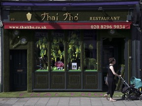 A woman pushes her buggy past Thai Tho restaurant bedecked in a Wimbledon motif within walking distance of the All England Club during the Wimbledon Tennis Championships in London Monday, July 10, 2017. The presentation is one of several dozen on display throughout the village, which created a competition for businesses three years ago. (AP Photo/Tim Ireland)
