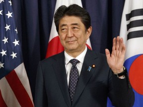 FILE - In this July 6, 2017 file photo, Japanese Prime Minister Shinzo Abe gestures as he meets with U.S. President Donald Trump and South Korean President Moon Jae-in before the Northeast Asia Security dinner in Hamburg. Poll numbers for Japanese Prime Minister Abe's Cabinet have nosedived to record lows since his return to power in 2012, adding a setback to his ruling party's recent crushing defeat in Tokyo city assembly elections. (AP Photo/Evan Vucci, File)