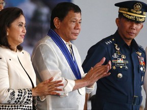 FILE - In this July 4, 2017 file photo, Philippine President Rodrigo Duterte, center, and Vice President Leni Robredo, left, applaud at the conclusion of the 70th anniversary celebration of the Philippine Air Force at Clark Freeport Zone in Pampanga province, north of Manila, Philippines. President Duterte has asked Congress to extend martial law in the southern third of the country until the end of the year, saying the rebellion there will not be quelled by July 22, the end of his 60-day martial law proclamation.(AP Photo/Bullit Marquez, FIle)