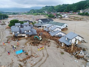 Firefighters inspect the collapsed houses in the mud following the flooding caused by heavy rain in Asakura, Fukuoka prefecture, southwestern Japan, Saturday, July 8, 2017.  The southern island of Kyushu suffered heavy rain after Typhoon Nanmadol swept across Japan earlier in the week, dumping large amounts of rain that damaged homes, roads and rice fields. (Koji Harada/Kyodo News via AP)