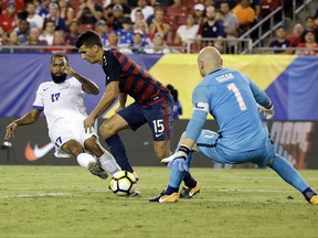 Martinique's Kevin Parsemain (17) takes a shot on goal past United States' Eric Lichaj (15) as United States goalkeeper Brad Guzan blocks the shot during a CONCACAF Gold Cup soccer match, Wednesday, July 12, 2017, in Tampa, Fla. United States won 3-2. (AP Photo/John Raoux)