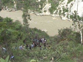 This screen grab from video shows rescuers looking for survivors and bodies of victims after an inter-city bus plunged into a deep gorge near Rampur Bushahar, Himachal Pradesh state, India, Thursday, July 20, 2017. (K.K.Productions via AP)