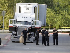 San Antonio police officers investigate the scene Sunday, July 23, 2017, where eight people were found dead in a tractor-trailer loaded with at least 30 others outside a Walmart store in stifling summer heat in what police are calling a horrific human trafficking case,  in San Antonio. (AP Photo/Eric Gay)