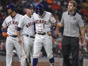 Houston Astros' Carlos Correa (1) walks off the field with manager AJ Hinch, second from left, after an injury during the fourth inning of the team's baseball game against the Seattle Mariners, Monday, July 17, 2017, in Houston. (AP Photo/Eric Christian Smith)