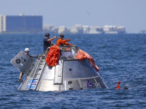 In this Thursday, July 13, 2017 photo, NASA astronaut Victor Glover signals back up to astronaut Daniel Burbank that he is OK after jumping into the Gulf of Mexico from the Orion capsule the astronauts are using to practice an emergency egress situation during recovery testing about four miles off of Galveston Island, Texas. The testing is the first time since the Apollo program that NASA has practiced such egress techniques from a capsule in open water. (Mark Mulligan/Houston Chronicle via AP)