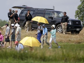 Golf spectators walk past presidential security during the third round of the U.S. Women's Open Golf tournament Saturday, July 15, 2017, in Bedminster, N.J. (AP Photo/Seth Wenig)