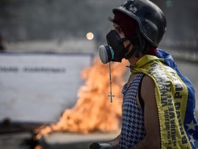 A Catholic rosary hangs from a gas mask worn by a demonstrator during a protest in Caracas, Venezuela, on Sunday, July 30, 2017