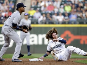 Seattle Mariners' Ben Gamel, right, tumbles after being tagged out on a run-down as New York Yankees second baseman Starlin Castro looks toward first during the first inning of a baseball game Thursday, July 20, 2017, in Seattle. (AP Photo/Elaine Thompson)
