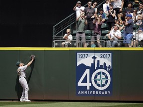 Oakland Athletics center fielder Jaycob Brugman watches as a fan tries to catch the home run ball of Seattle Mariners' Nelson Cruz in the fourth inning of a baseball game Sunday, July 9, 2017, in Seattle. (AP Photo/Elaine Thompson)