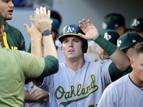 Oakland Athletics' Ryon Healy is congratulated in the dugout after scoring on a single by Jaycob Brugman during the second inning of a baseball game against the Seattle Mariners, Saturday, July 8, 2017, in Seattle. (AP Photo/John Froschauer)