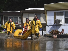 Members of Pleasant Prairie, Wis., and Somers, Wis., Fire Departments assist Mary Knoebel from her trailer during flooding in Pleasant Prairie, Wis., Wednesday, July 12, 2017. Flooding has forced the evacuation of the mobile home park in southeastern Wisconsin.  (Bill Siel/The Kenosha News via AP)