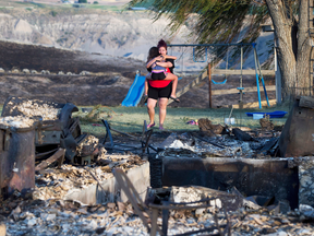 Kelsey Thorne holds her daughter Nevaeh Porter, 8, as they cry while viewing the remains of their home that was destroyed by a wildfire on the Ashcroft First Nation, near Ashcroft, B.C., July 9, 2017.