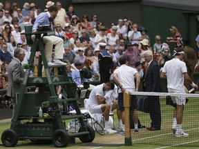 Umpire Damien Dumusois checks on Croatia's Marin Cilic as he receives treatment during the Men's Singles final match against Switzerland's Roger Federer, right, on day thirteen at the Wimbledon Tennis Championships in London Sunday, July 16, 2017. (AP Photo/Tim Ireland)