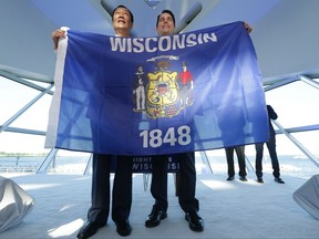 Foxconn Chairman Terry Gou, left, and Gov. Scott Walker hold the Wisconsin flag to celebrate their $10 billion investment to build a display panel plant in Wisconsin, at the Milwaukee Art Museum in Milwaukee, Wis., Thursday, July 27, 2017. (Mike De Sisti/Milwaukee Journal-Sentinel via AP)