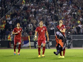 FILE - In this file photo dated Tuesday, Oct. 14, 2014, Serbia's Stefan Mitrovic grabs a banner containing the Albanian flag attached to a drone flying above the pitch during the Euro 2016 Group I qualifying match between Serbia and Albania in Belgrade, Serbia. The banner prompted fan violence with the match was suspended, and a man who claims to have flown the drone has been detained but it is revealed Saturday July 29, 2017, that Albania's soccer federation is calling on Albanian authorities to stop his extradition to Serbia. (AP Photo/Darko Vojinovic, FILE)