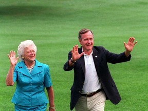 FILE- This Aug. 24, 1992 file photo shows President Bush, right, and first lady Barbara Bush walking with their dog Millie across the South Lawn as they return to the White House. (AP Photo/Scott Applewhite, File)