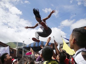 A woman is launched into the air during a pro-government candidates' rally in Caracas, Venezuela, Tuesday, July 25, 2017. Across Venezuela, pro-government candidates to the Constitutional Assembly held their last campaign rallies ahead of Sunday's historical vote. (AP Photo/Ariana Cubillos)