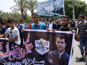 Hundreds of supporters of exiled former Gaza strongman Mohammed Dahlan carry a banner with his picture during a protest against metal detectors Israel erected at the Al-Aqsa Mosque compound in Jerusalem, in Gaza City, Thursday, July 20, 2017. A potentially groundbreaking power-sharing deal between two former political foes is slowly unfolding in Hamas-ruled Gaza. In the latest signs of the Egypt-backed understandings moving forward, supporters of Dahlan, a former Hamas nemesis, have been allowed to open a Gaza office and have begun disbursing large sums of Dahlan-procured Gulf aid to Gaza's needy. (AP Photo/Adel Hana)