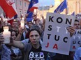 Anti-government protesters raise candles and placards reading "Constitution", as they gather in front of the Supreme Court in Warsaw, Poland, Sunday, July 23, 2017. Protests continue across Poland over plans by the populist ruling party Law and Justice to put the Supreme Court and the rest of the judicial system under the party's political control.