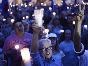 Anti-government protesters raise candles, as they gather in front of the Supreme Court in Warsaw, Poland, Sunday, July 23, 2017. Protests continue across Poland over plans by the populist ruling party Law and Justice to put the Supreme Court and the rest of the judicial system under the party's political control. (AP Photo/Alik Keplicz)