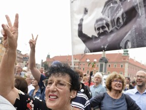 Government critics with a portrait of former President Lech Walesa shout slogans during a protest against monthly observances by Poland's ruling party in memory of President Lech Kaczynski and 95 others killed in a 2010 plane crash, in Warsaw, Poland, Monday, July 10, 2017. The protesters say that the remembrance observances are being used for political purposes by Kaczynski's twin brother, Jaroslaw, who is the ruling party leader. (AP Photo/Alik Keplicz)