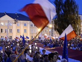 Anti-government protesters raise candles and wave flags, as they gather in front of the Supreme Court in Warsaw, Poland, Saturday, July 22, 2017. Protests have broken out across Poland over plans by the populist ruling party Law and Justice to put the Supreme Court and the rest of the judicial system under the party's political control. (AP Photo/Alik Keplicz)