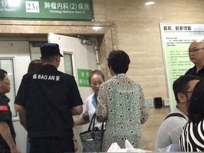 In this image take from video, security guards and a medical staff member talk to a visitor as they stand guard at an entrance door of the oncology medicine ward inside the First Hospital of China Medical University where imprisoned Chinese Nobel Peace Prize laureate and dissident Liu Xiaobo is believed to have been transferred to after being diagnosed with late-stage liver cancer in Shenyang in northeastern China's Liaoning province, Thursday, July 13, 2017. Liu's condition is now life threatening with multiple organ failure, and his family has opted against inserting a breathing tube needed to keep him alive, the hospital treating him said on Wednesday. (AP Photo/Ng Han Guan)