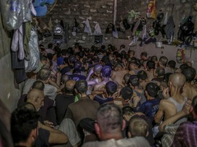 Suspected Islamic State member sit inside a small room in a prison south of Mosul, Tuesday, July 18, 2017. Hundreds of suspected Islamic State members swept up by Iraqi forces in Mosul are being held in a cramped and stifling prison just outside the city. (AP Photo/Bram Janssen)