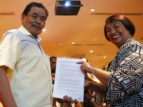 Mohagher Iqbal, left, chair of the Moro Islamic Liberation Front's peace panel, and his counterpart from the Government Irene Santiago, hold documents following the signing of the joint communications plan for the implementation of the Bangsamoro Basic Law (BBL) Monday, July 17, 2017 in Manila, Philippines. The two panels will submit later Monday to President Rodrigo Duterte the draft of the BBL which still needs approval by the Philippine Congress and for ratification through a plebescite.(AP Photo/Bullit Marquez)