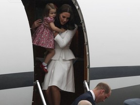 Britain's Kate, the Duchess of Cambridge holds Princess Charlotte as they arrive at the airport, in Warsaw , Poland, Monday, July 17, 2017. The Duke and Duchess of Cambridge and their children have arrived in Poland, the first leg of a goodwill trip to two European Union nations that seeks to underscore Britain's friendly ties despite its negotiations to leave the bloc. Prince William is in the foreground.  (AP Photo/Czarek Sokolowski)