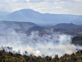 A smoke rises over Montenegro capital Podgorica, Montenegro, Monday, July 17, 2017. At least 100 tourists have been forced to evacuate from a coastal area in Montenegro that has been the hardest hit by the blaze. Fueled by strong winds and dry weather, the fire on the Lustica peninsula in southern Montenegro has spread near to homes and camping zones. (AP Photo/Risto Bozovic)