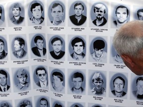 A man looks at a banner with pictures of Serbs killed by Bosnian forces during the 1992-95 Bosnian war in the Srebrenica area, in downtown Belgrade, Serbia, Monday, July 10, 2017. (AP Photo/Darko Vojinovic)